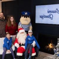 Two siblings with matching blue GVSU zipups with Santa, Louie, and parents